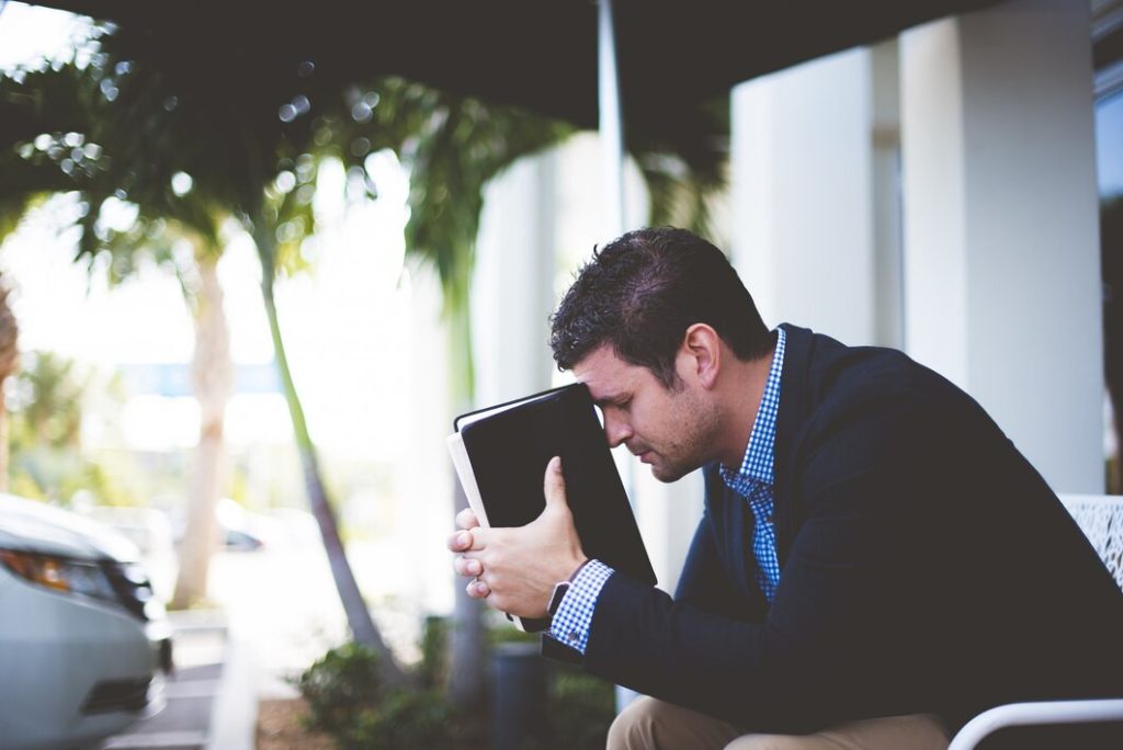 Person sitting at a desk with their head in their hands
