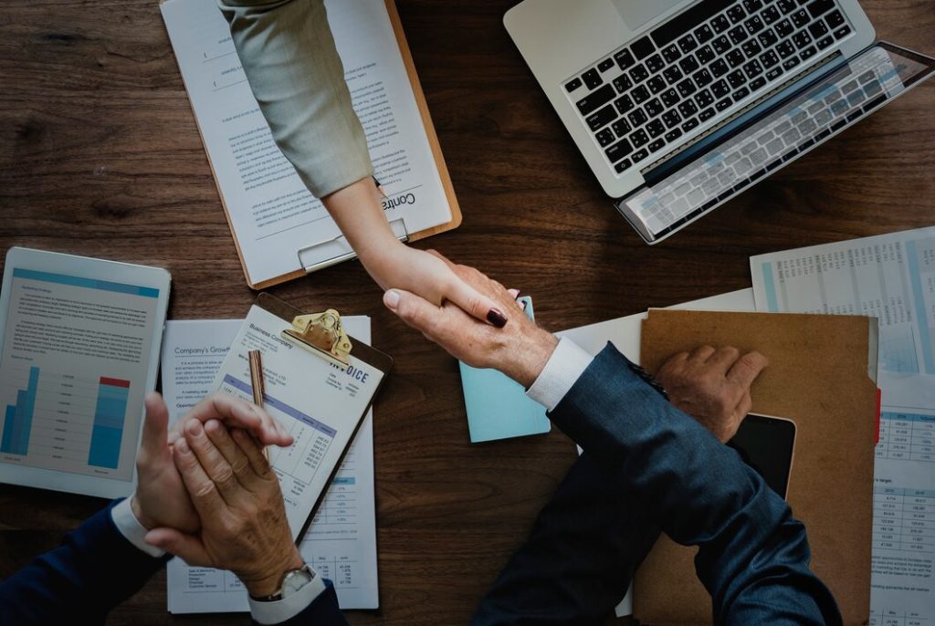 Handshake over a desk with printed charts