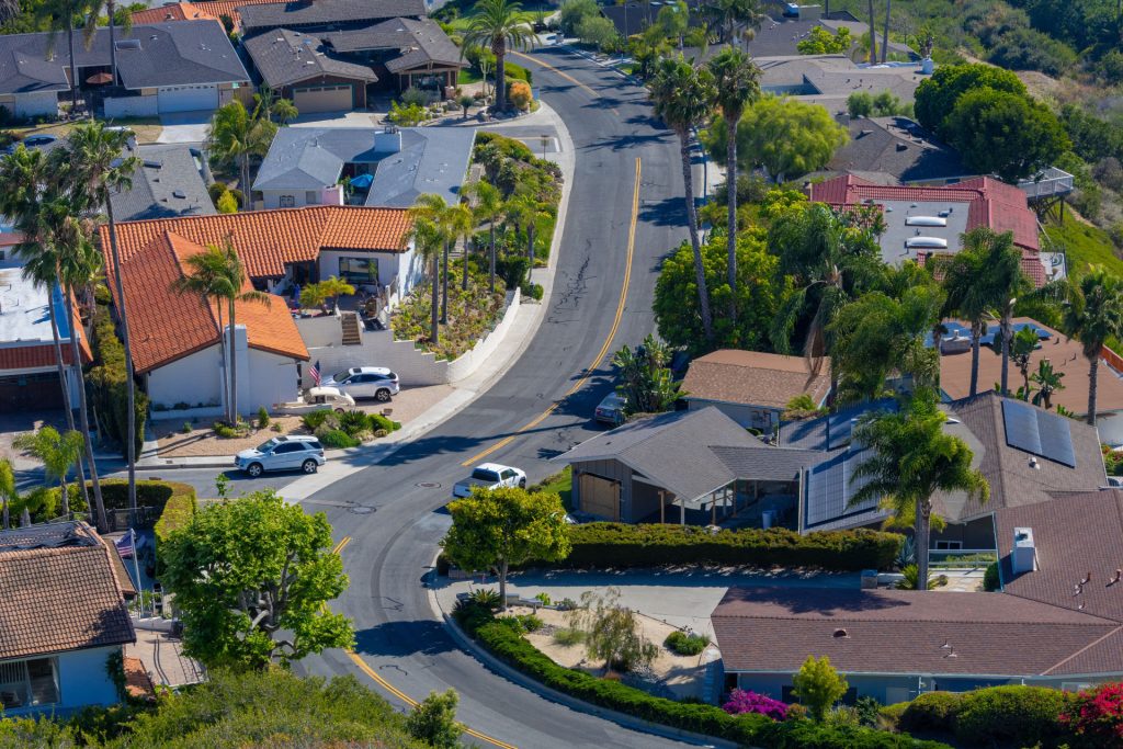 An aerial view of a winding suburban street lined with houses, palm trees, and cars near the office of a business lawyer in Calabasas.