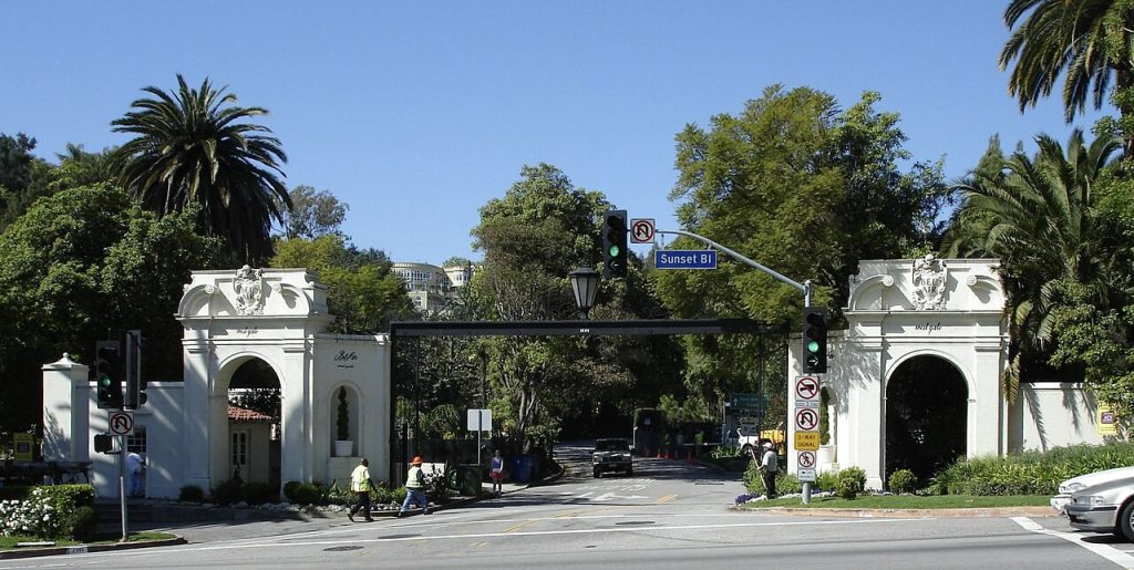 The West Gate entrance to Bel-Air, featuring white arched pillars and a street sign for Sunset Boulevard, where a business lawyer in Bel Air might work.