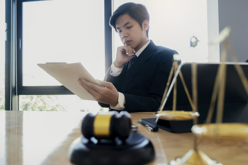 A Los Angeles business lawyer in a suit reviews a document at a desk with a gavel and a scale of justice.