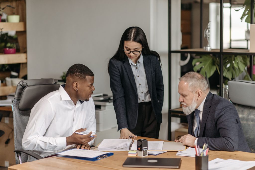 Three people in business attire reviewing documents with a business lawyer in Marina del Rey at a table.