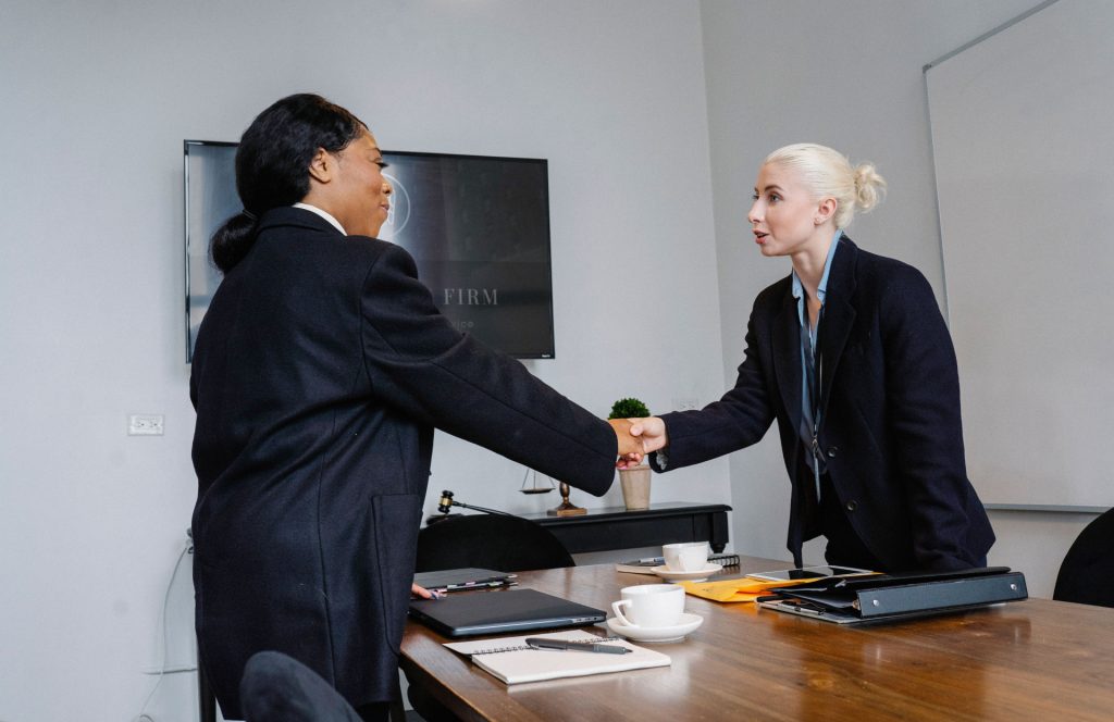 A business lawyer in Monrovia shakes hands with a professional over a conference table in an office.