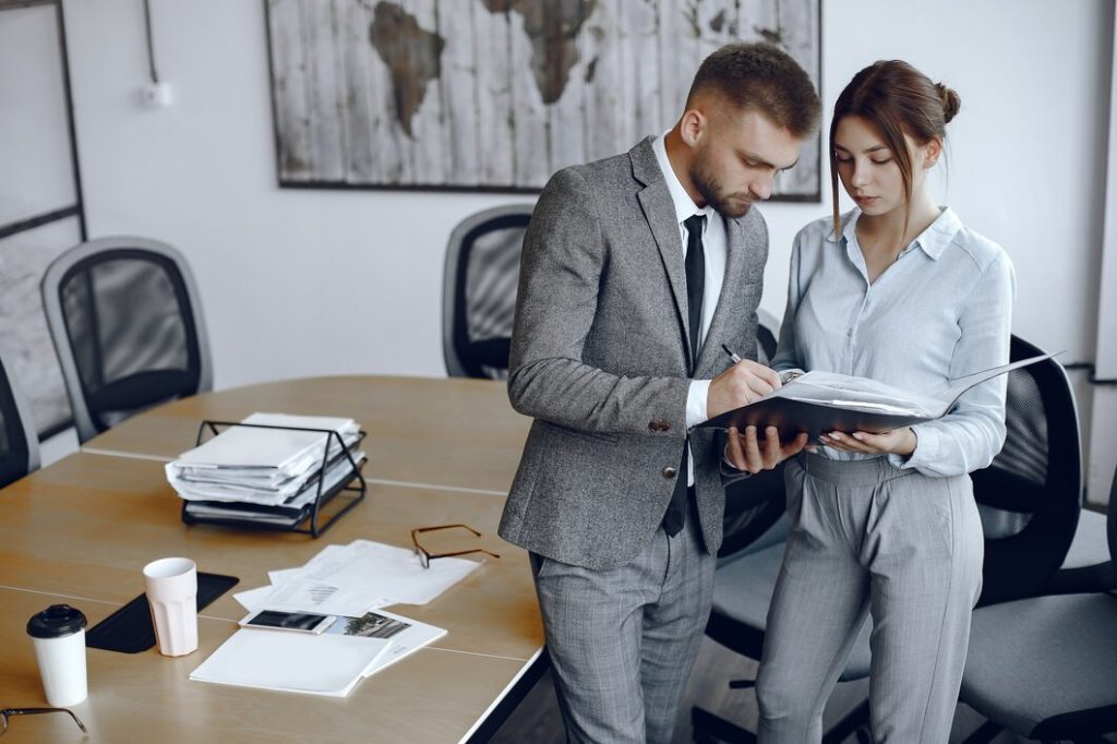 A business lawyer in Newport Beach and a woman in business attire review documents together in an office.