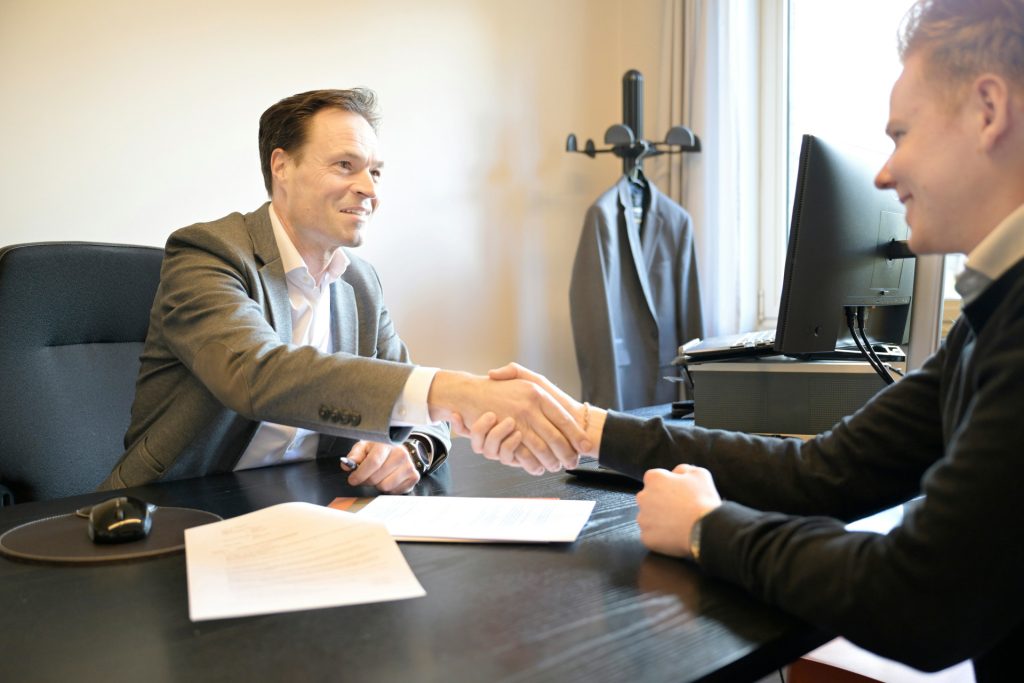 Two men shaking hands across a desk in a Redondo Beach business lawyer’s office.