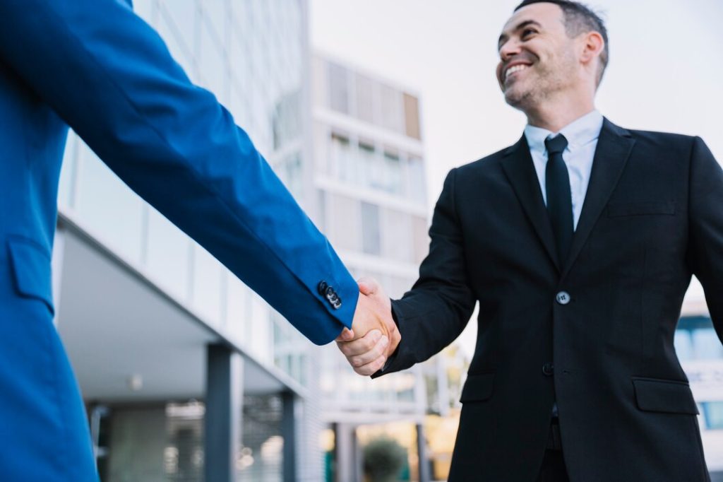 Two professionals, including a business lawyer in Rowland Heights, shaking hands outside an office building.