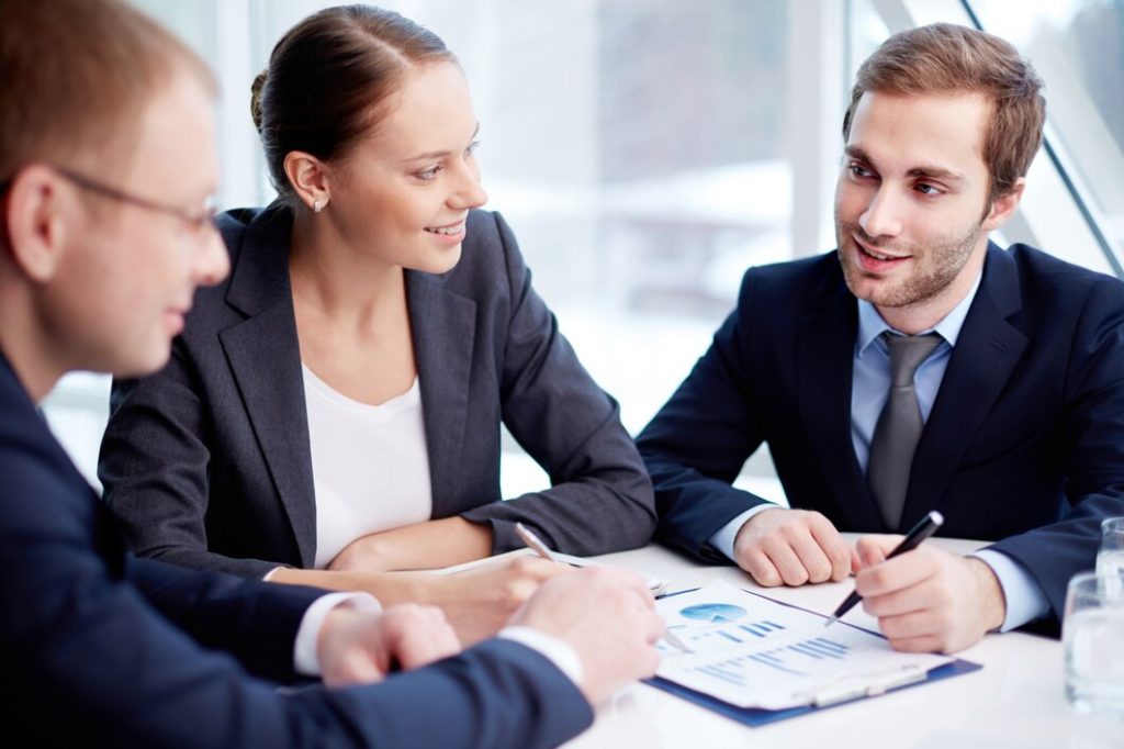 Three business lawyers in San Fernando discuss a document with charts at a table.