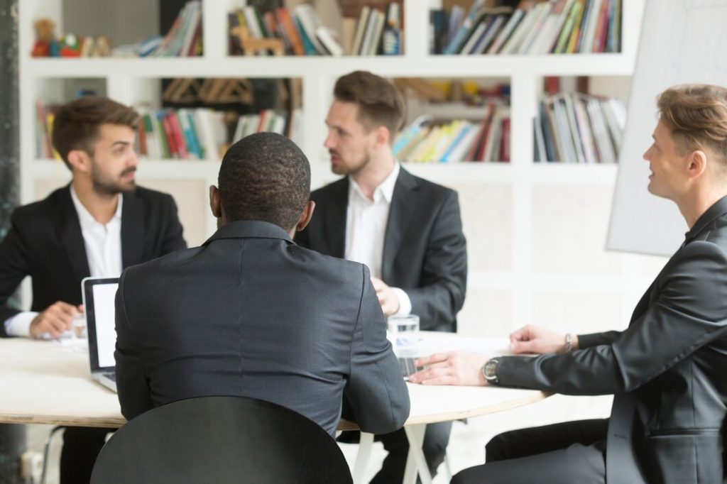 Four business lawyers in suits sitting around a conference table during a meeting in San Gabriel.