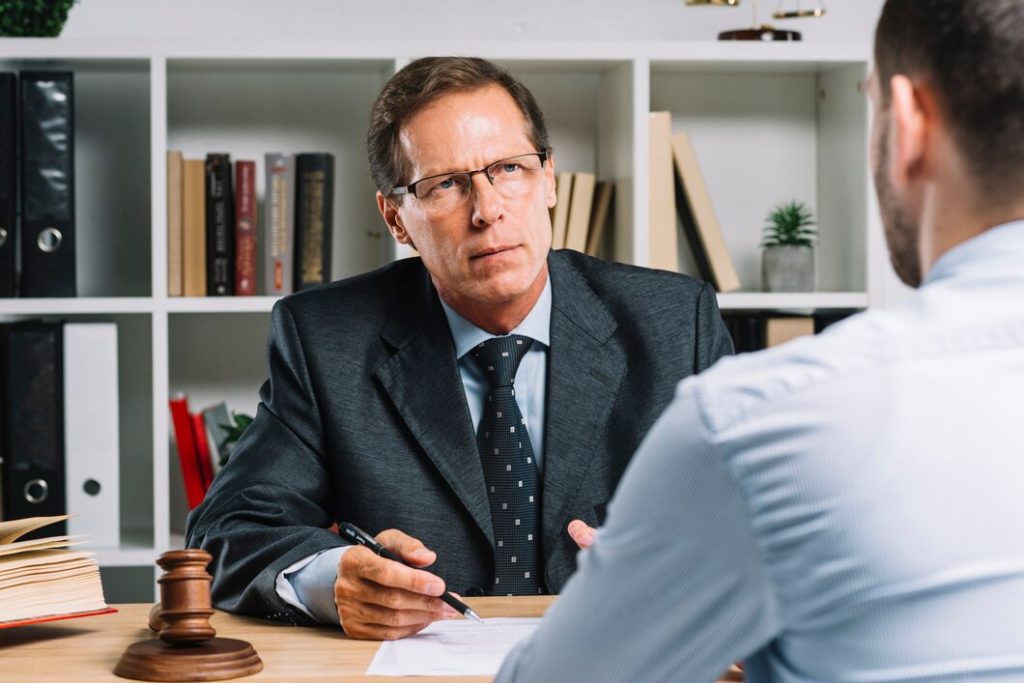 A business lawyer in Sylmar sits at a desk with a wooden gavel, speaking to a client in an office.