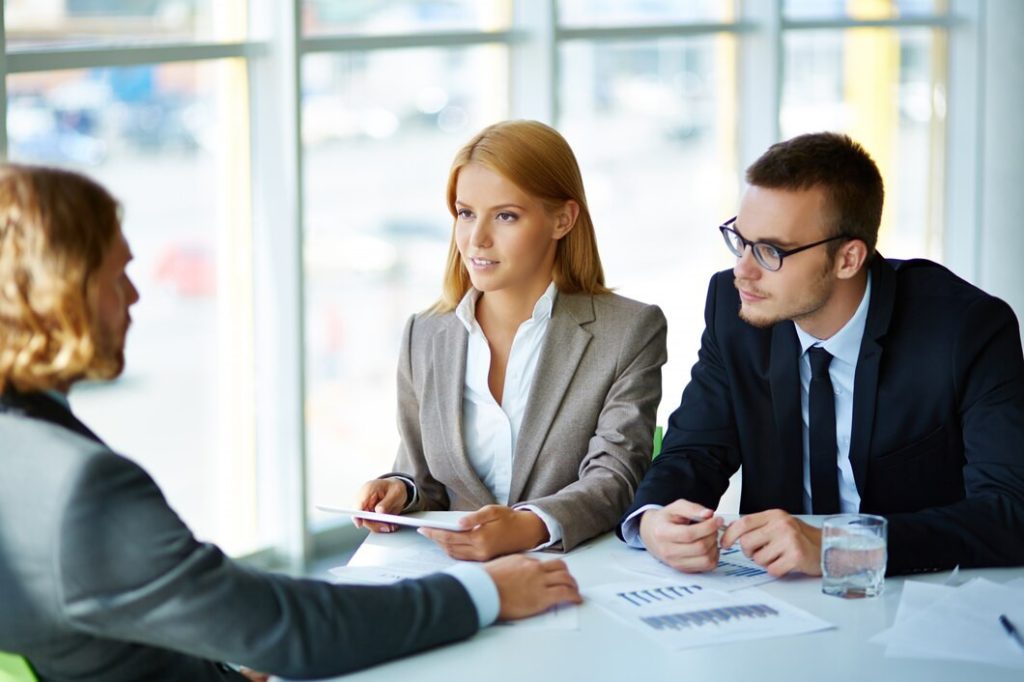Two business lawyers from Toluca Lake interview a candidate across a desk.