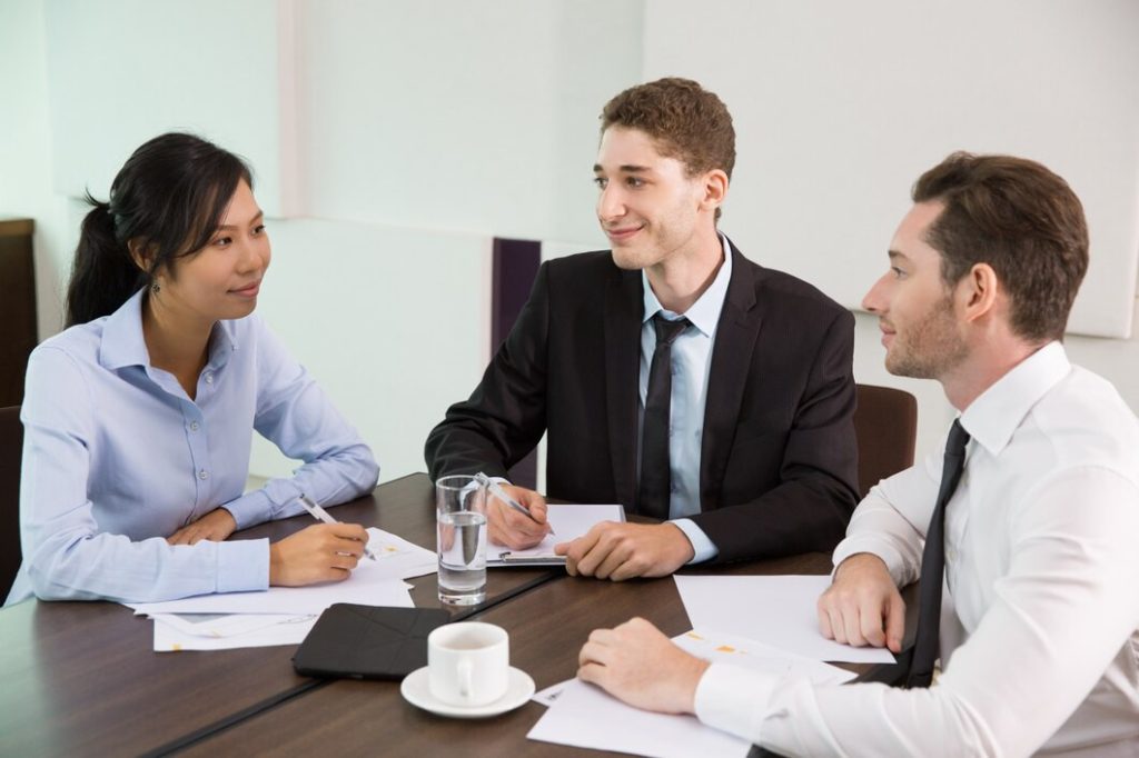 Three business lawyers in Woodland Hills sit around a conference table during a meeting.