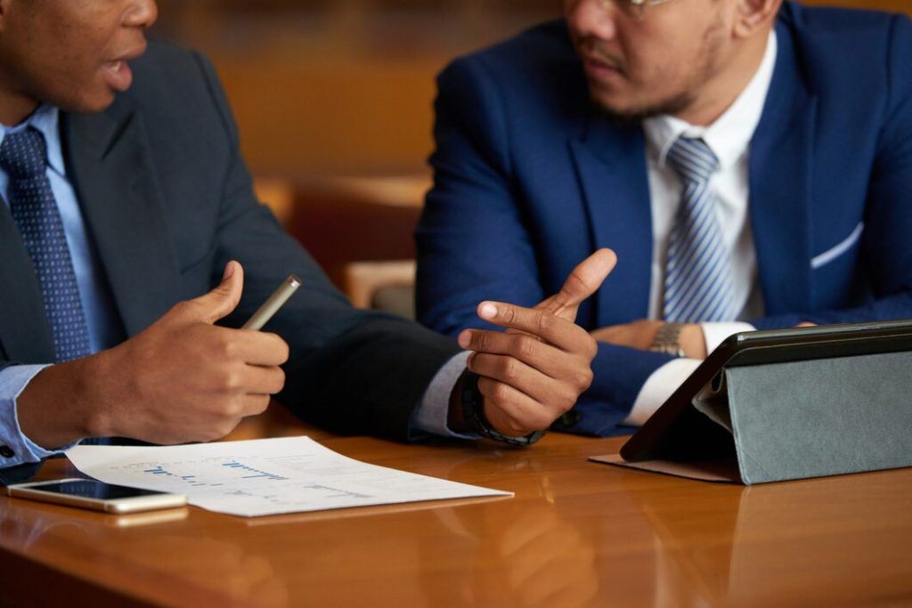 Two business lawyers in Yorba Linda sit at a table with documents and a tablet, engaged in a discussion.