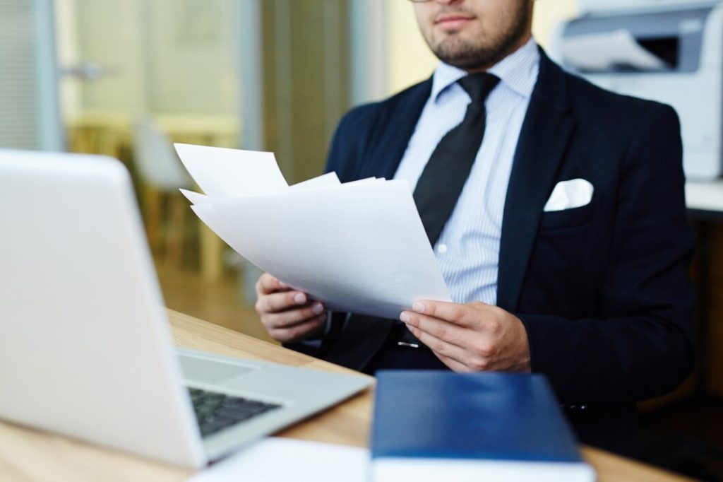 A business lawyer in Alhambra sits at a desk reviewing a stack of documents.