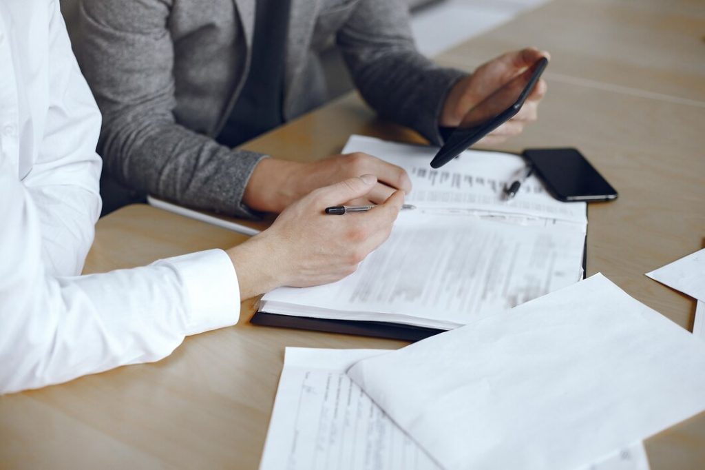 Two people in business attire reviewing documents and using a tablet at a desk with a business lawyer in Alhambra.