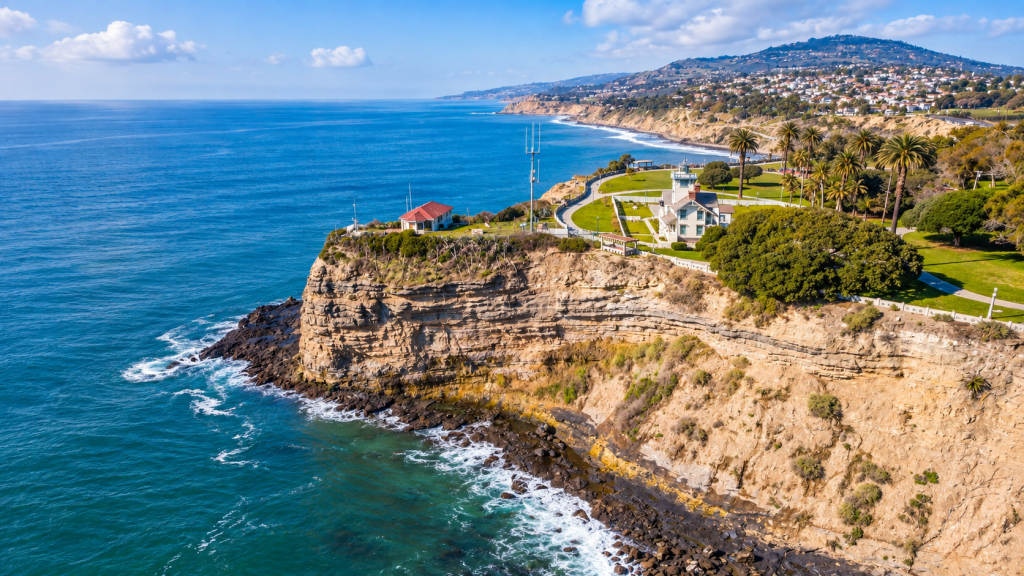 Aerial view of the Point Vicente Lighthouse on a rocky cliff overlooking the ocean, near where a business lawyer in San Pedro might work, with the Palos Verdes coastline in the distance.