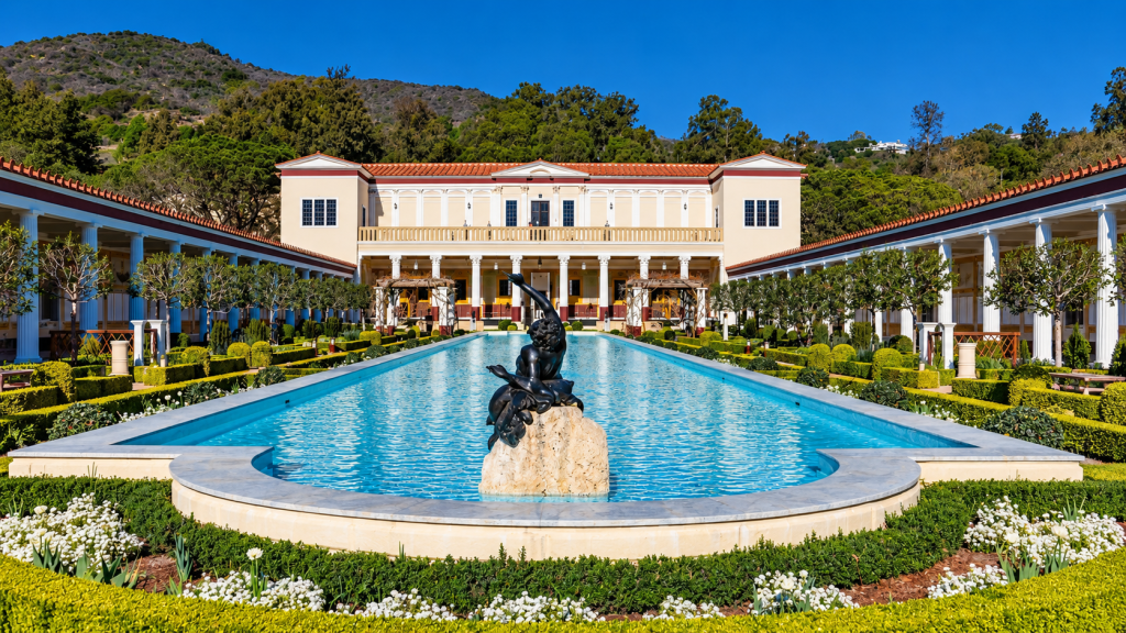 A long reflecting pool with a central bronze fountain, flanked by colonnades, manicured hedges, and a villa hillside view suitable for a Greater Los Angeles business lawyer.