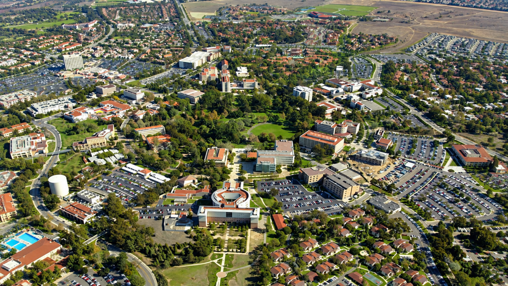 Aerial view of a sprawling university campus in the area where a business lawyer serving Orange County might work, showing multiple buildings, parking lots, and landscaped grounds.
