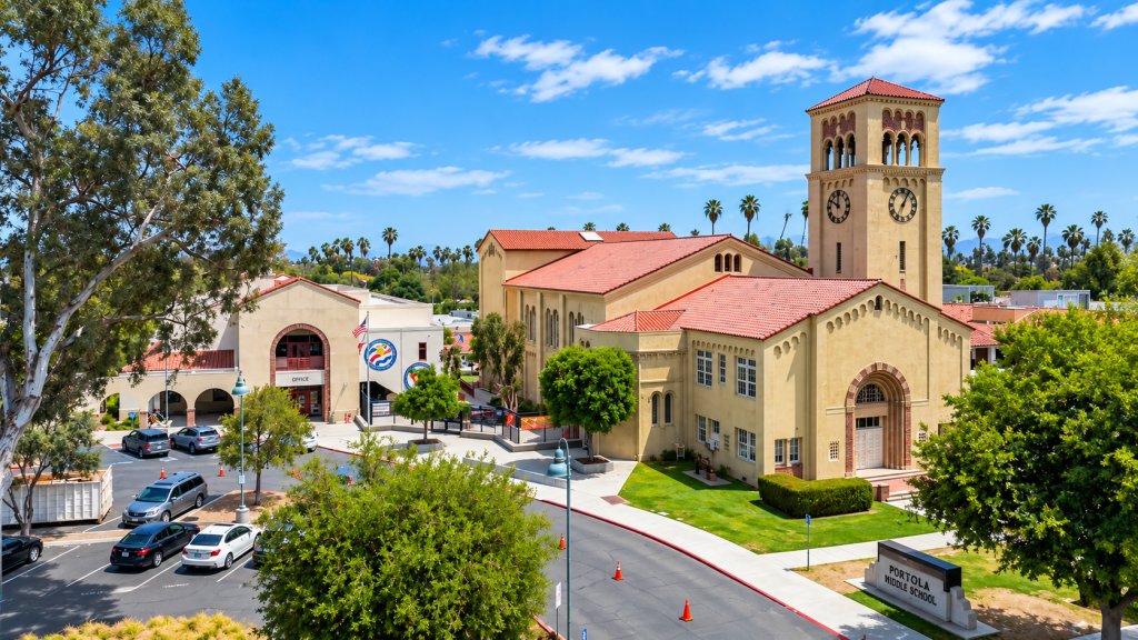 Aerial view of the Portola Middle School campus near a business lawyer in South Pasadena, featuring a Spanish-style building with a central clock tower, surrounding grounds, and a parking lot.