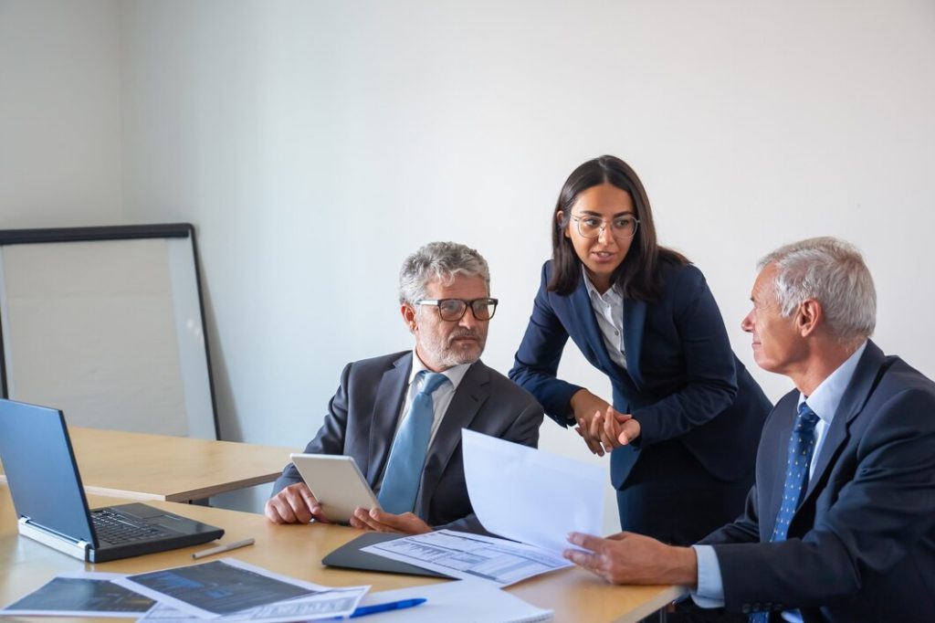 Three business lawyers in Studio City collaborate around a desk with laptops and documents.