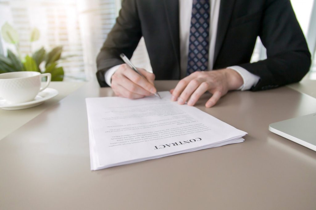 A business lawyer in Hancock Park sits at a desk and signs a contract.