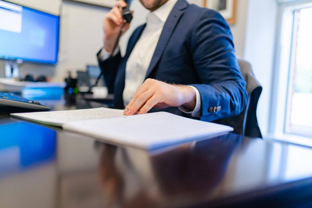 A business attorney in a blue suit jacket talks on the phone while reviewing a document at a desk in downtown Los Angeles.