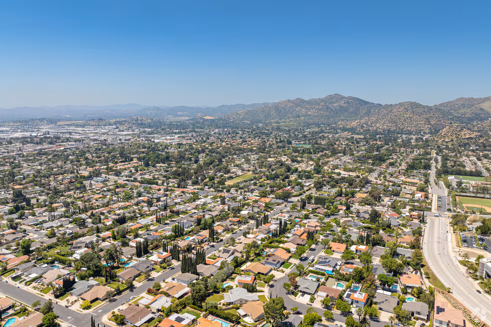 Aerial view of a residential neighborhood near Chatsworth, featuring houses and trees set below distant mountains under a clear sky.