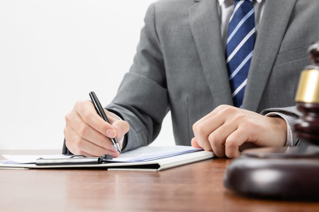A business lawyer in Granada Hills writes on a document next to a wooden gavel.