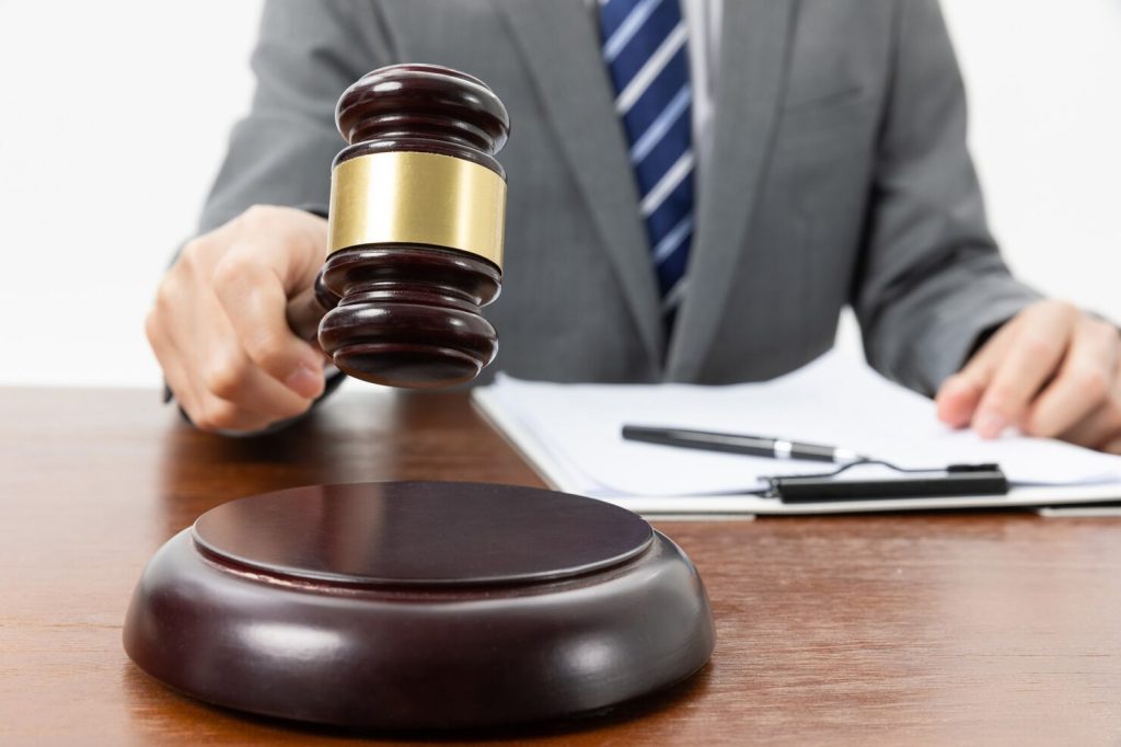 A business lawyer in Century City striking a wooden gavel onto a sound block on a desk.
