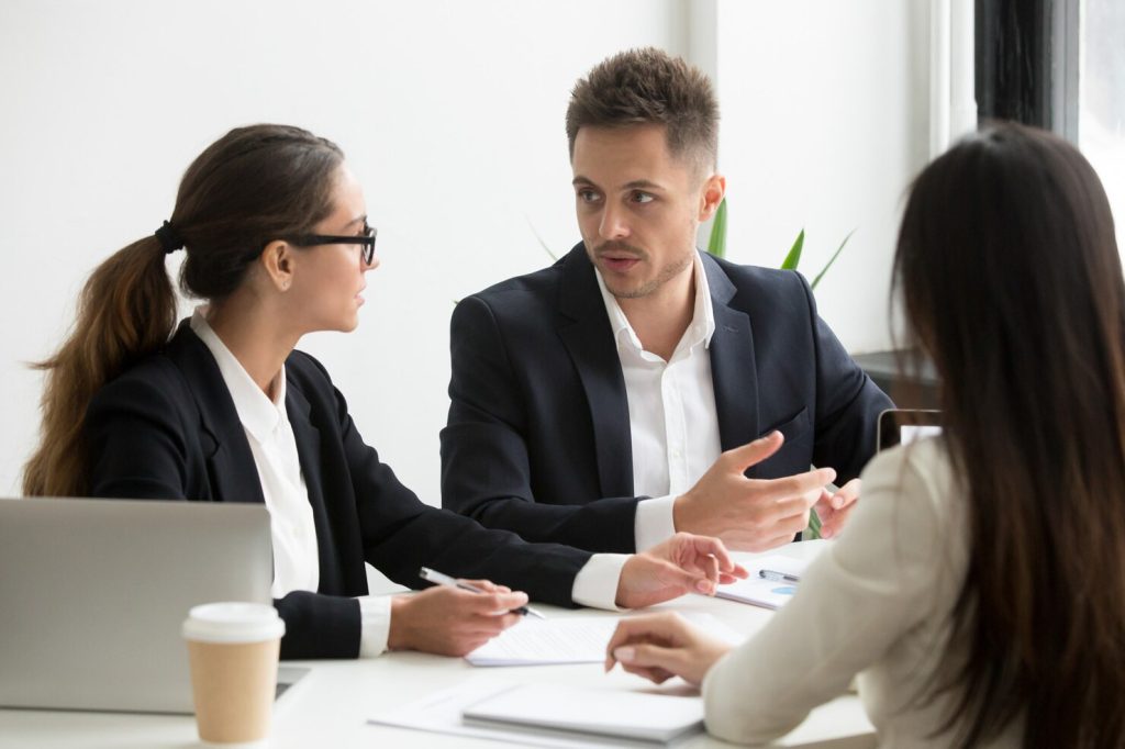 Three professionals sitting at a table discussing business documents with a business lawyer in Claremont.