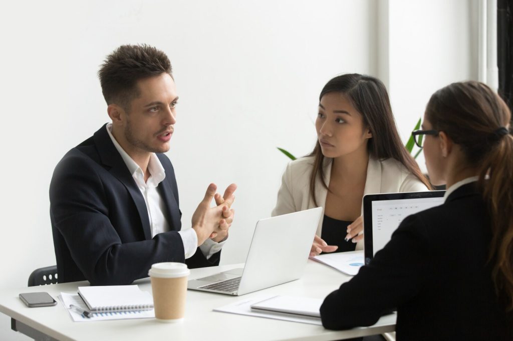 Three professionals sitting at a table during a business disputes law firm meeting.