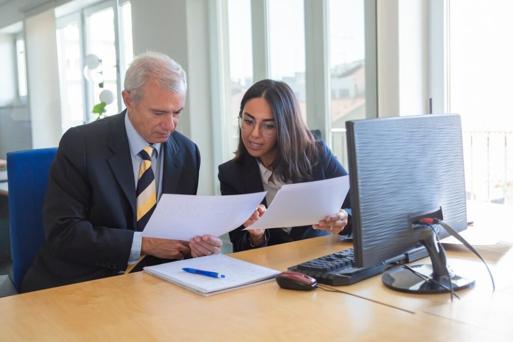 A business lawyer in Bel Air and a woman in business attire reviewing documents at an office desk.