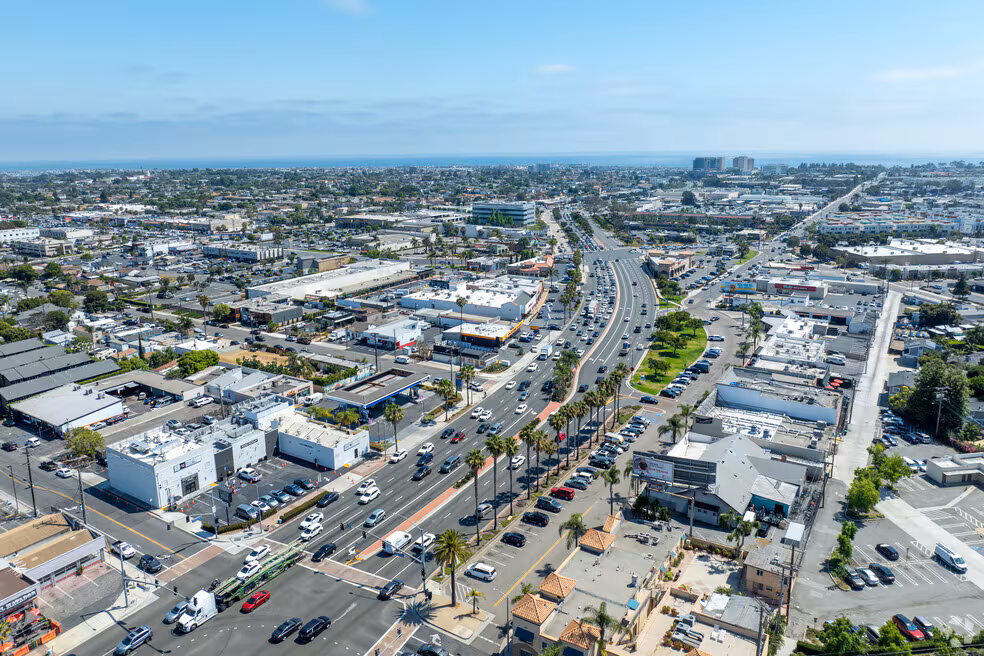Aerial view of a coastal road running through a Costa Mesa business district with commercial buildings and palm trees.