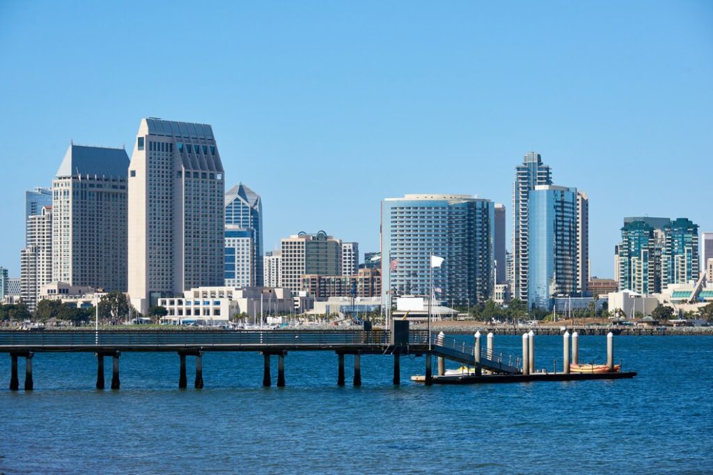 The San Diego skyline seen across a bay with a wooden pier in the foreground, near the office of a business disputes lawyer.
