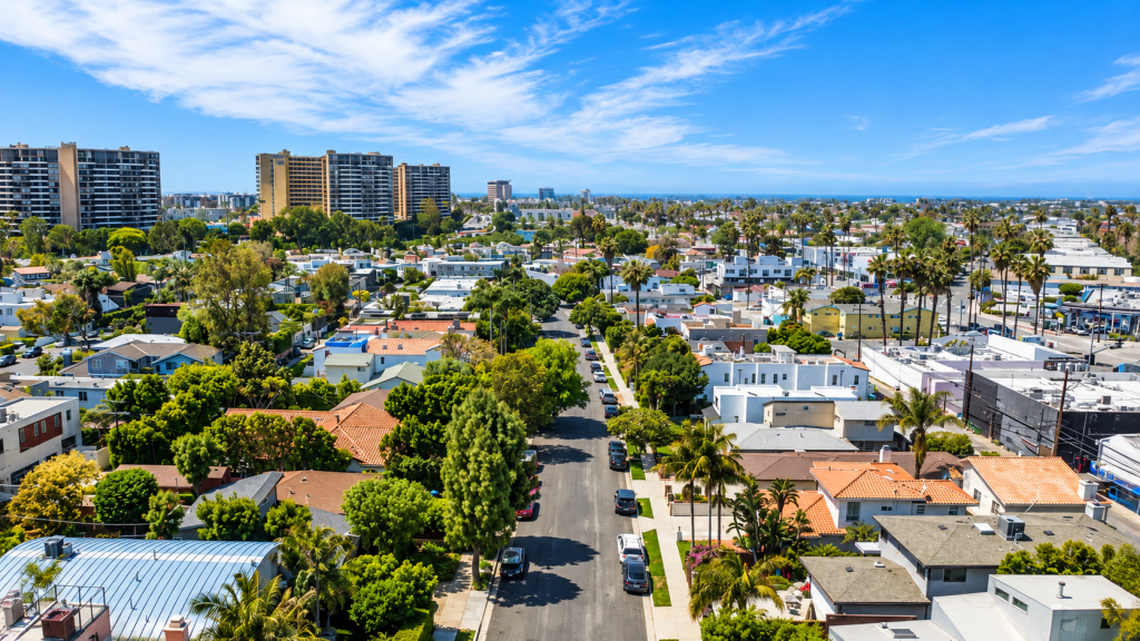 Aerial view of a residential neighborhood in Marina del Rey with palm trees, houses, and high-rise apartment buildings under a bright blue sky.