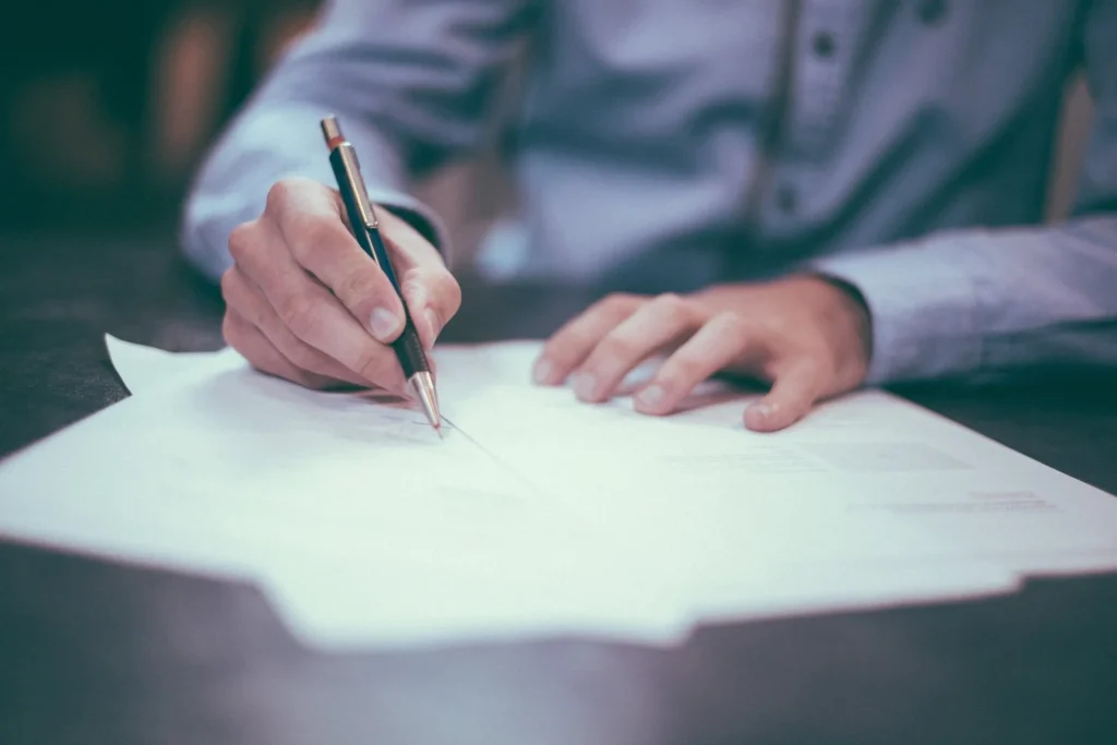 Person writing with a pen on a document
