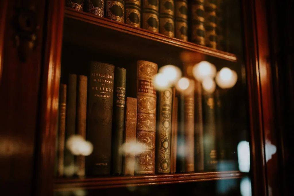 Antique business law books with gold-embossed spines arranged on wooden shelves inside a glass-fronted cabinet.