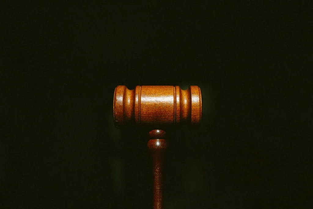A wooden judge’s gavel representing corporate compliance requirements, isolated against a black background.