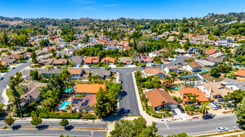 Aerial view of a suburban neighborhood where a business lawyer in Pomona might work, showing houses, tree-lined streets, and a crossroad intersection.