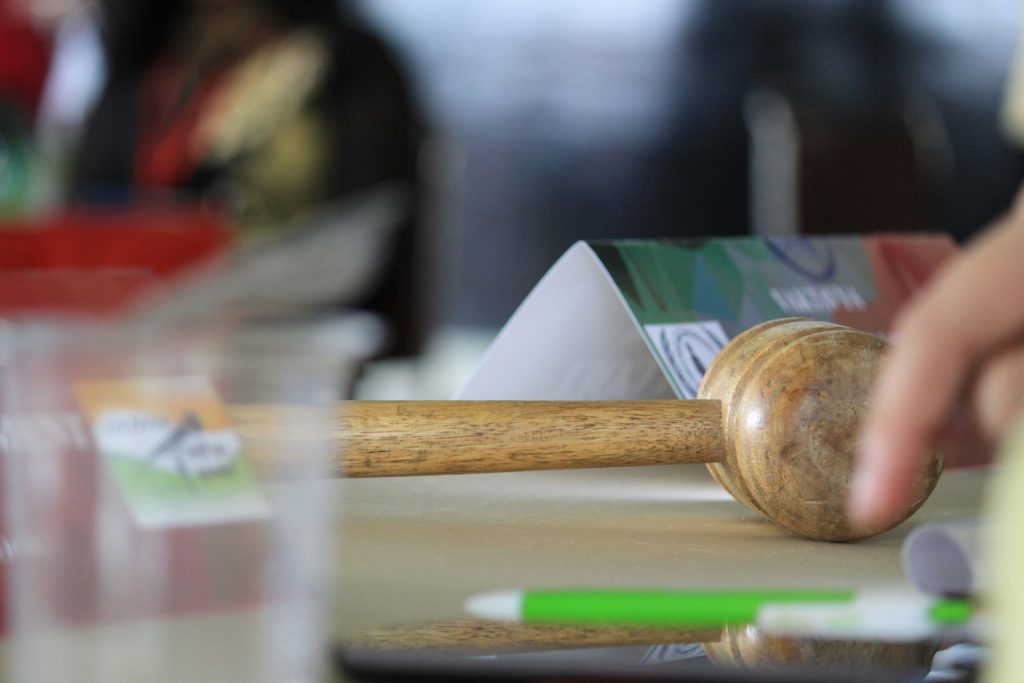 A wooden gavel rests on a table next to a folded program and a pen, the tools of a business lawyer in Diamond Bar.