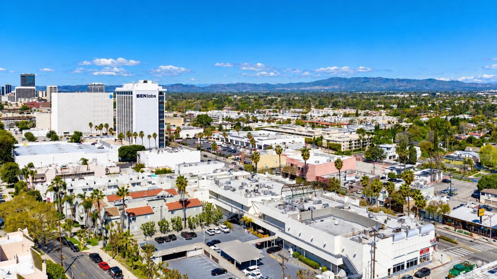 Aerial view of a San Fernando Valley business district, featuring the BENlabs building surrounded by low-rise commercial structures with distant mountains under a blue sky.