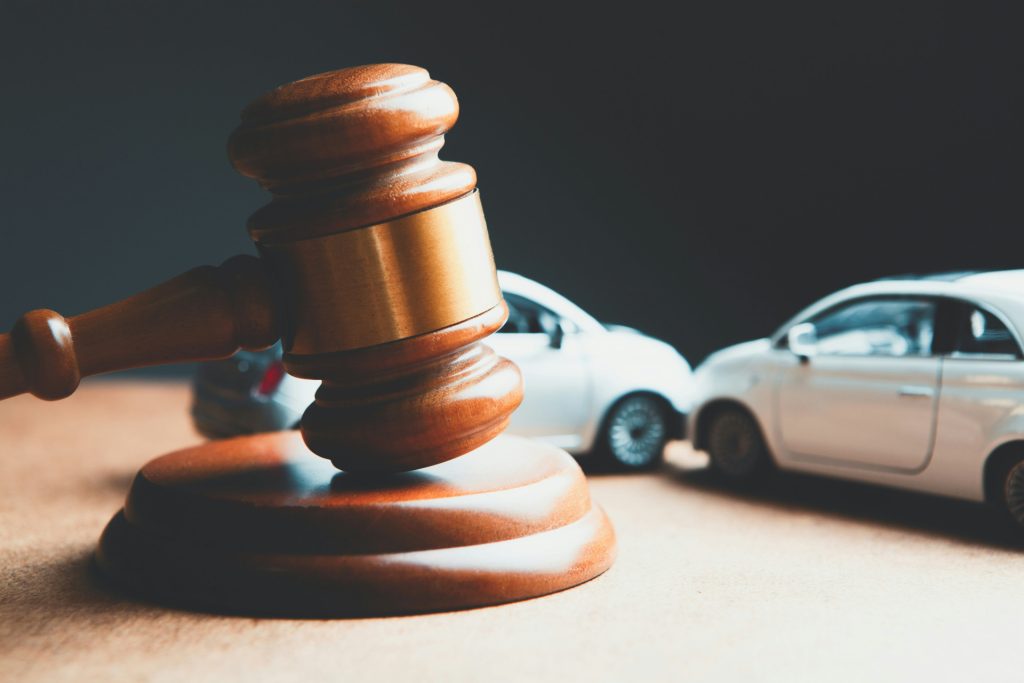 A wooden judge’s gavel positioned in front of two miniature toy cars on a desk for a business lawyer in Culver City.