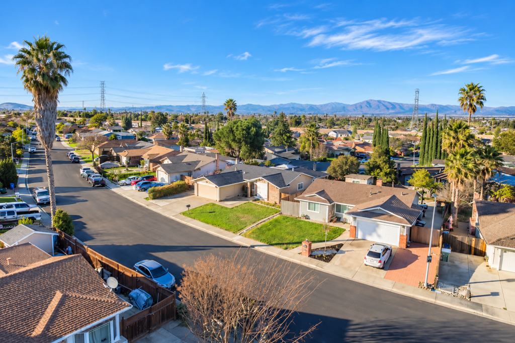 Aerial view of a residential neighborhood in Woodland Hills with single-story homes, palm trees, and distant mountains under a blue sky.