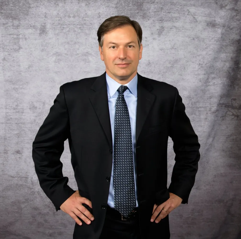 A Lurie & Associates business litigation lawyer in a suit and tie stands with his hands on his hips.